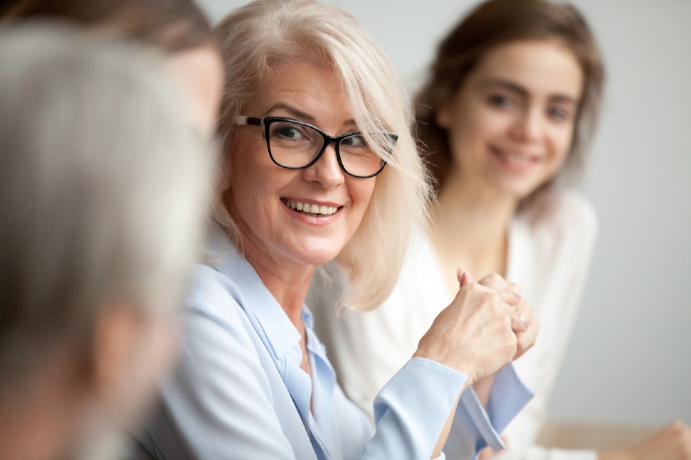 woman with glasses in conversation with other women